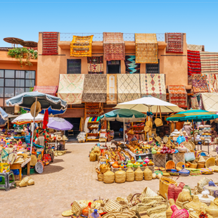 Uitzicht op Marrakech met roodkleurige gebouwen, palmbomen verspreid door de stad onder een heldere lucht.